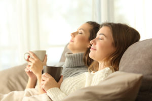 Two Women Relaxing On The Couch With Coffee